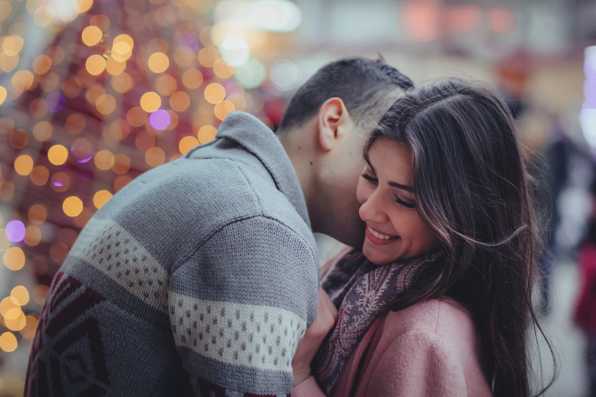 A man, face hidden, and a hesitant woman embrace.