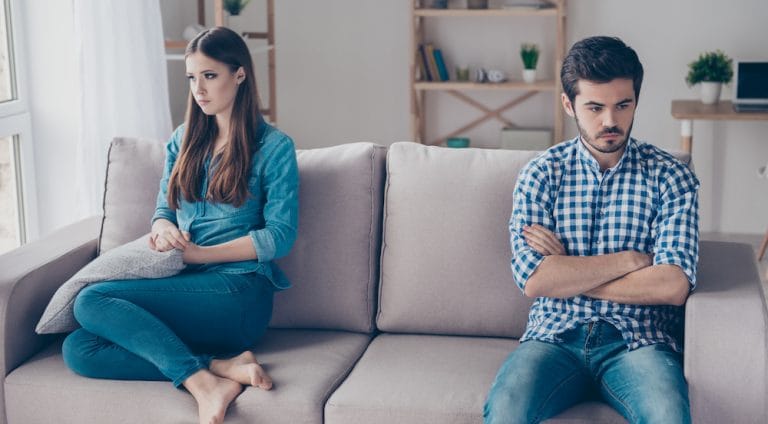 Annoyed couple is ignoring each other, sitting on the couch