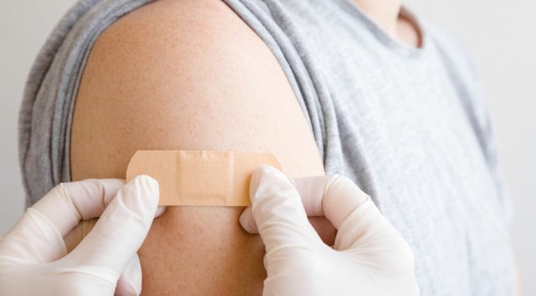 Doctor in white rubber protective gloves applying adhesive bandage