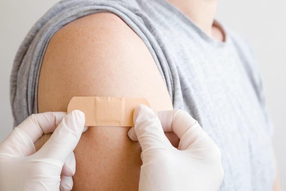 Doctor in white rubber protective gloves applying adhesive bandage