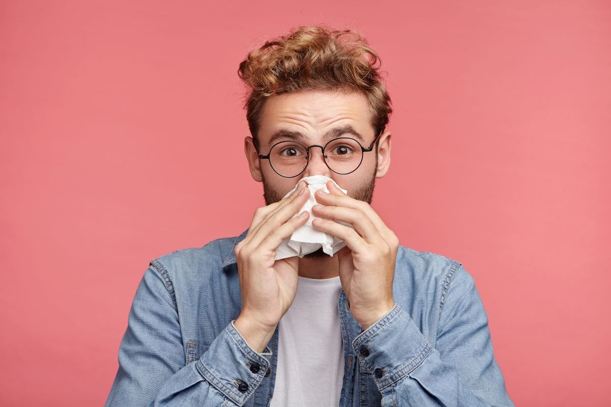 bearded man has running nose, rubs nose with handkerchief